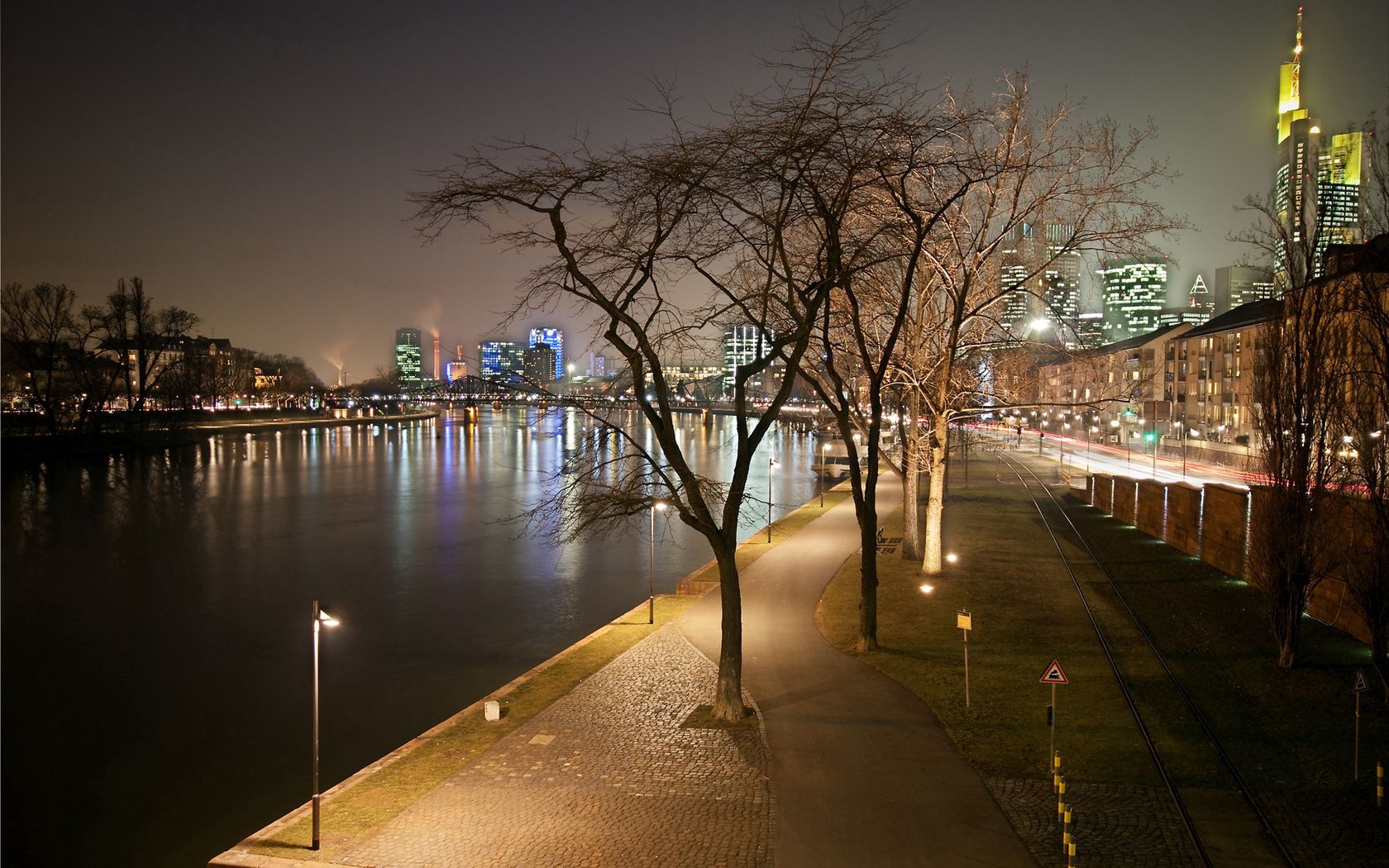 evening, frankfurt, channel, strait, water, boat, pier, lights, bridge, park, trees, railroad tracks, houses, buildings, skyscrapers, wall, distance, road