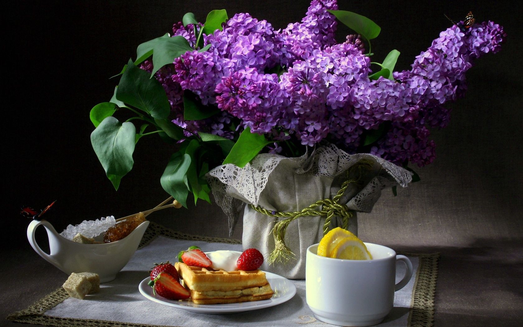 still life, flowers, lilac, butterfly, breakfast, waffles, strawberries, cup, lemon, sugar, cloth, dark background