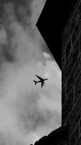 Preview wallpaper airplane, clouds, flight, building, black and white