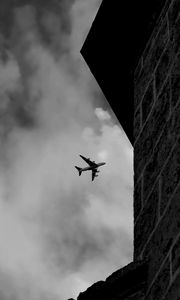 Preview wallpaper airplane, clouds, flight, building, black and white