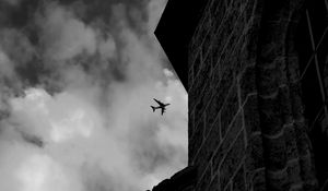 Preview wallpaper airplane, clouds, flight, building, black and white