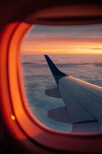 Preview wallpaper airplane, porthole, wing, sunset, clouds, sky