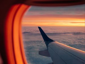 Preview wallpaper airplane, porthole, wing, sunset, clouds, sky