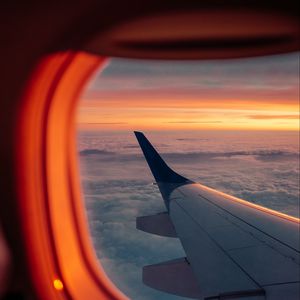 Preview wallpaper airplane, porthole, wing, sunset, clouds, sky