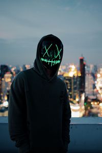 Preview wallpaper anonymous, mask, hood, hoodie, city, glow