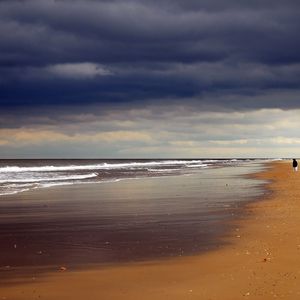 Preview wallpaper beach, sand, coast, ocean, person, loneliness, cloudy, emptiness