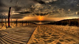 Preview wallpaper beach, sand, road, traces, fence, sun, evening, sky, decline, clouds