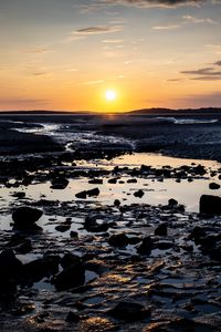 Preview wallpaper beach, sunset, water, stones, sand, sea, dusk