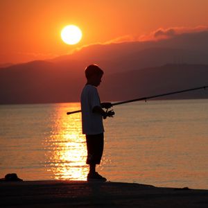 Preview wallpaper boy, river, lake, fishing, fishing rod, sunset, hills