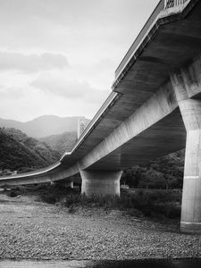 Preview wallpaper bridge, pilings, river, bw, mountains