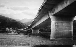 Preview wallpaper bridge, pilings, river, bw, mountains