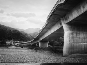 Preview wallpaper bridge, pilings, river, bw, mountains