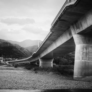 Preview wallpaper bridge, pilings, river, bw, mountains