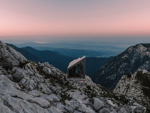 Preview wallpaper building, mountains, peaks, distance, sunset, stone