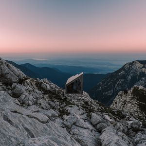 Preview wallpaper building, mountains, peaks, distance, sunset, stone