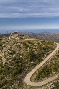 Preview wallpaper building, mountains, road, turn, aerial view