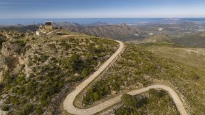 Preview wallpaper building, mountains, road, turn, aerial view
