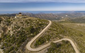 Preview wallpaper building, mountains, road, turn, aerial view