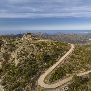 Preview wallpaper building, mountains, road, turn, aerial view
