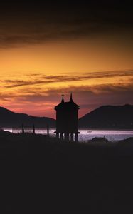 Preview wallpaper building, pilings, lake, mountains, silhouettes, evening