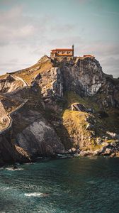 Preview wallpaper building, rocks, mountains, sea, road