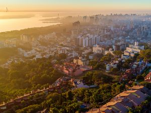 Preview wallpaper buildings, city, trees, sea, dawn, aerial view