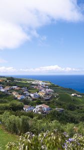 Preview wallpaper buildings, grass, hill, sea, sky, clouds