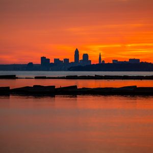 Preview wallpaper buildings, silhouettes, water, sunset, horizon, dark