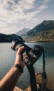 Preview wallpaper camera, lens, hand, mountains, focus