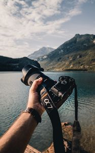 Preview wallpaper camera, lens, hand, mountains, focus