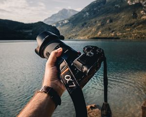Preview wallpaper camera, lens, hand, mountains, focus