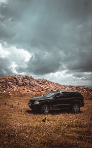 Preview wallpaper car, suv, side view, stones, sky