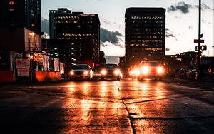 Preview wallpaper cars, headlights, light, road, buildings, twilight