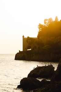 Preview wallpaper castle, coast, cliffs, sea, sunset