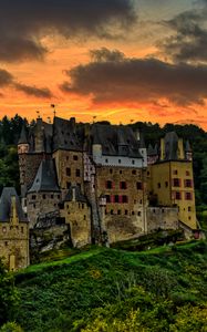 Preview wallpaper castle, mountain, trees, forest, hill, clouds, sunset, dark