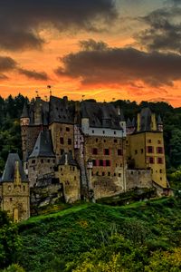 Preview wallpaper castle, mountain, trees, forest, hill, clouds, sunset, dark