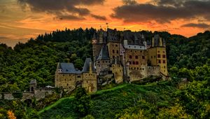 Preview wallpaper castle, mountain, trees, forest, hill, clouds, sunset, dark