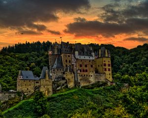 Preview wallpaper castle, mountain, trees, forest, hill, clouds, sunset, dark