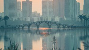 Preview wallpaper city, buildings, bridge, lake, sunset, sun