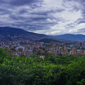 Preview wallpaper city, buildings, cityscape, aerial view, trees, mountains