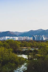 Preview wallpaper city, buildings, mountains, trees, river