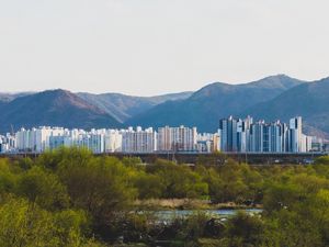 Preview wallpaper city, buildings, mountains, trees, river