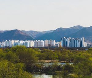 Preview wallpaper city, buildings, mountains, trees, river