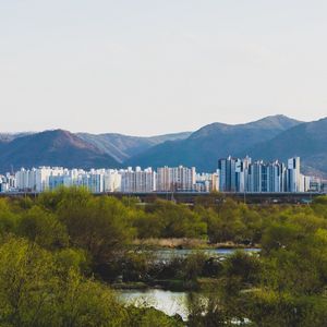 Preview wallpaper city, buildings, mountains, trees, river