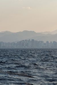 Preview wallpaper city, buildings, mountains, sea, waves, fog