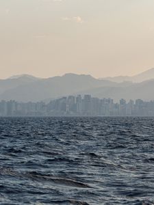 Preview wallpaper city, buildings, mountains, sea, waves, fog