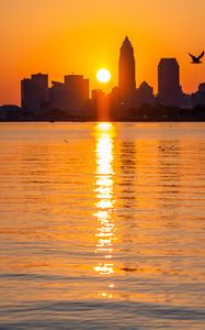 Preview wallpaper city, buildings, silhouettes, water, sunset, sun, dark