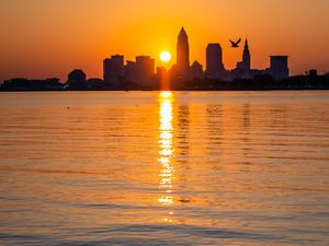 Preview wallpaper city, buildings, silhouettes, water, sunset, sun, dark