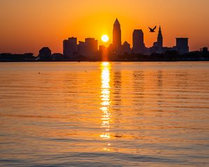 Preview wallpaper city, buildings, silhouettes, water, sunset, sun, dark