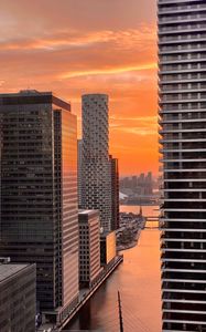 Preview wallpaper city, buildings, water, sunset, aerial view